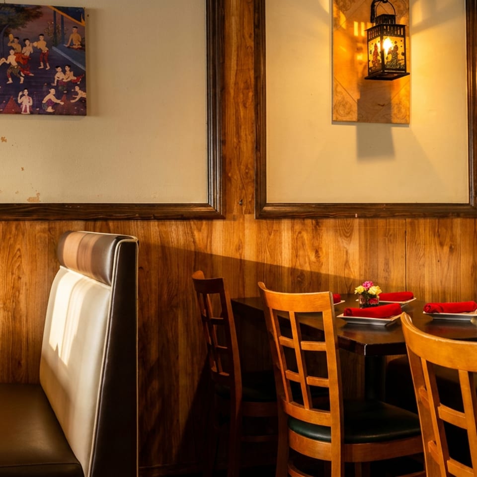 Cozy restaurant interior with wooden paneling, booths, tables set with red napkins, and a decorative lantern.